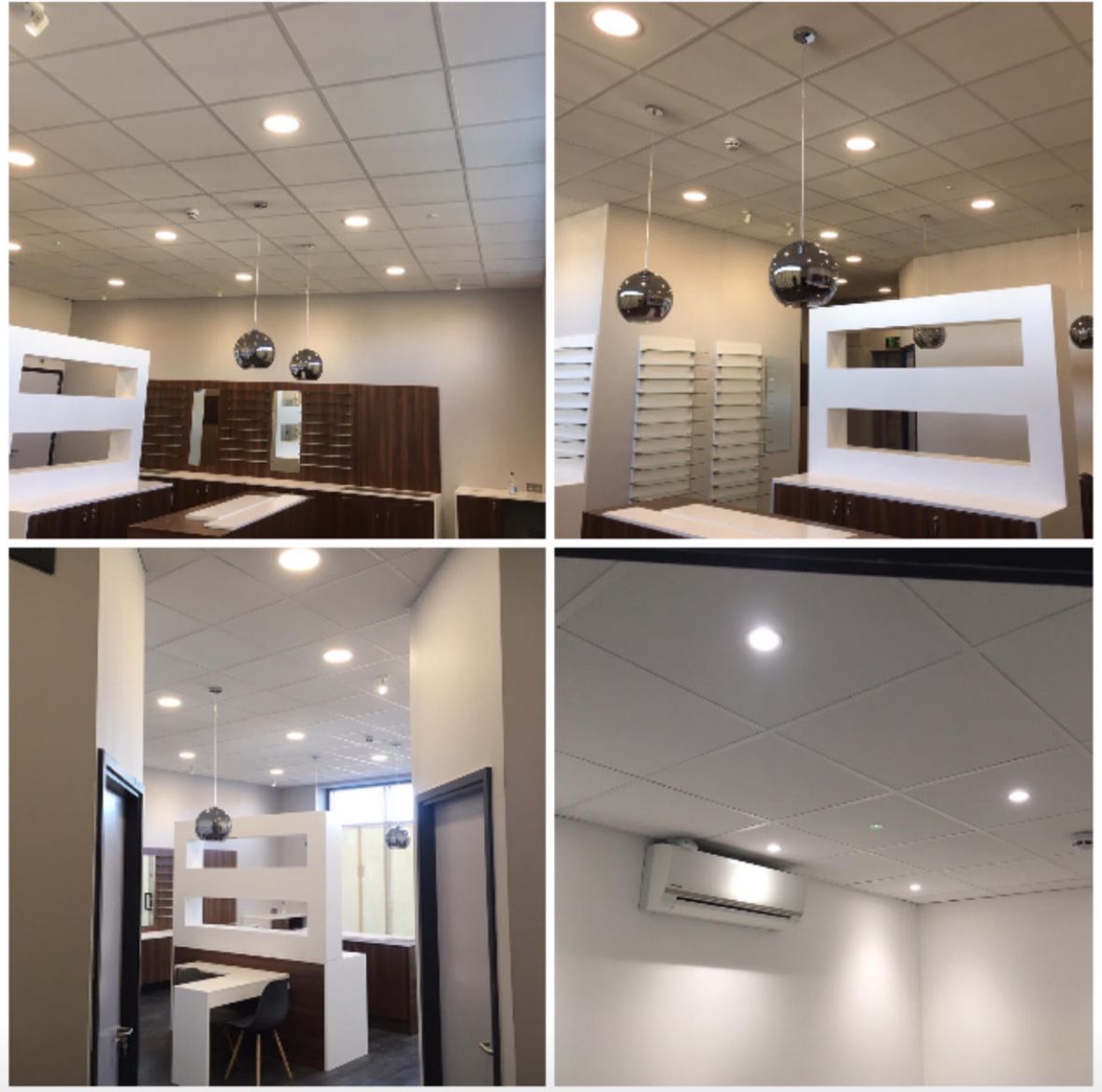 Modern office interior with ceiling lights, pendant lamps, white walls, and wooden furniture.