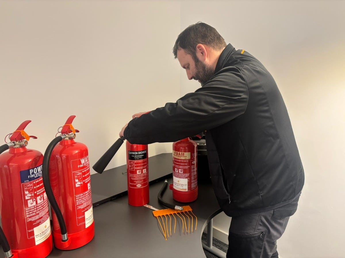 A man inspecting fire extinguishers on a table in an indoor setting.